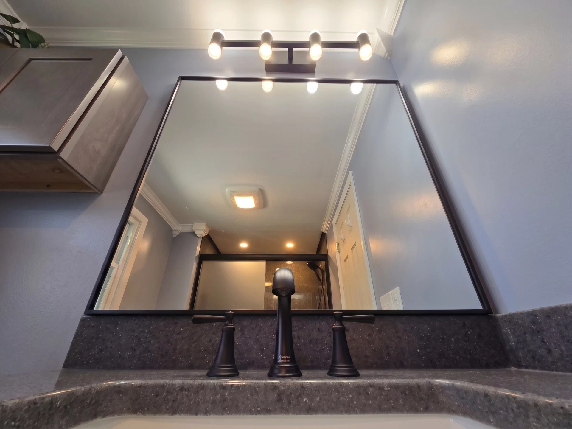 New vanity mirror and lighting installed above custom vanity during Camillus bathroom renovation