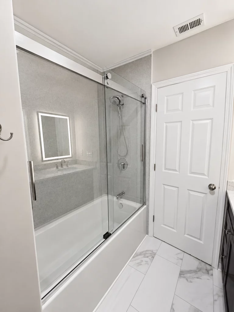 A porcelain enamel bath tub with double sliding barn shower door installed as part of a larger bathroom remodel in Baldwinsville, NY