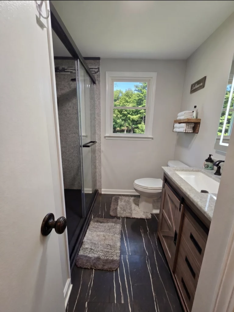 Completed East Syracuse bathroom remodel featuring a custom Onyx Collection walk-in shower, custom vanity, and luxury vinyl plank flooring.