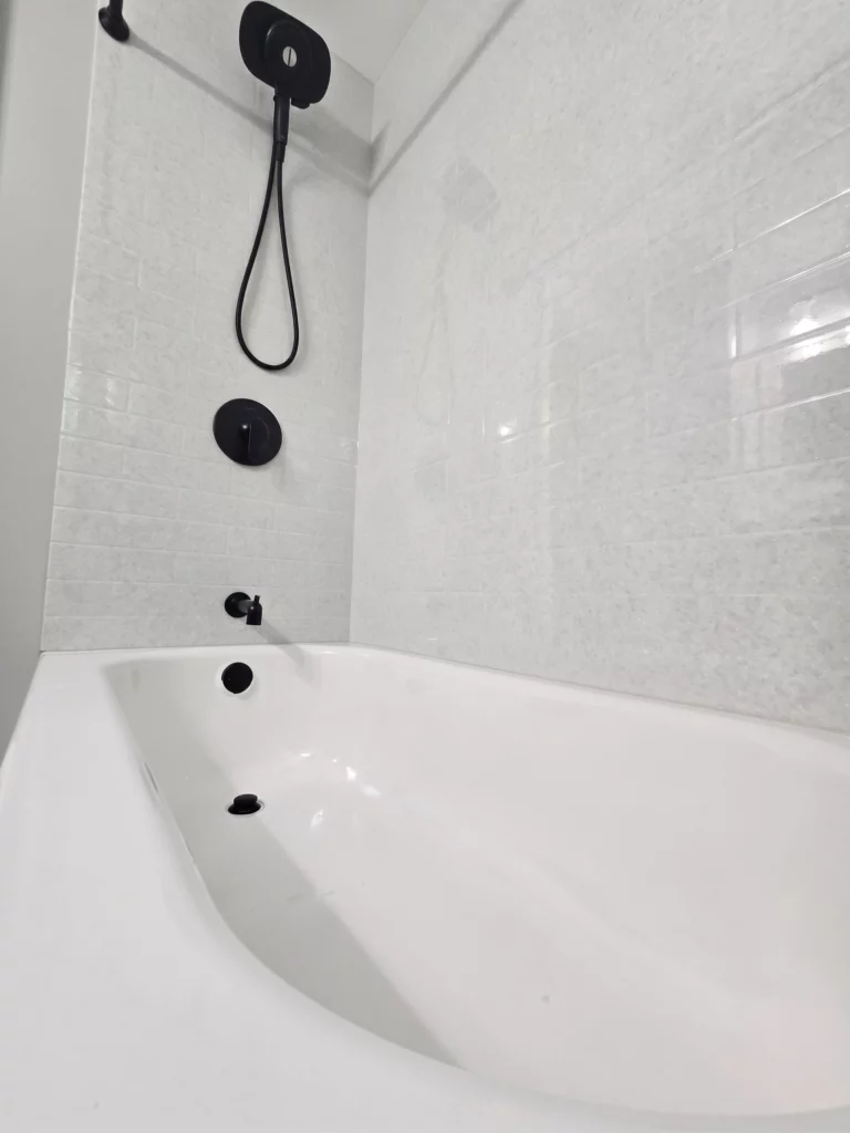 A new porcelain bathtub with Onyx Collection cultured stone walls and American Standard premium fixtures